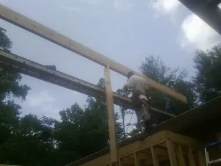 Carpenter setting a ridge beam over a new addition frame — Ice Dam Removal by Roofing Brothers in Ramsay